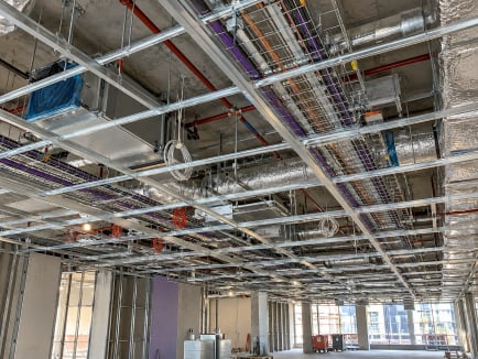 Open ceiling during construction showing ceiling grid, cable trays, ductwork and services before the ceiling is closed