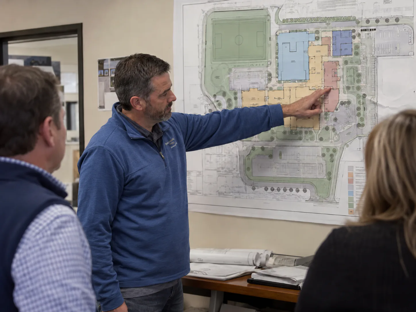 Staff reviewing a school site plan on the wall to agree paging zones across buildings and outdoor areas